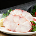 Whole scarlet rockfish on dark slate with ice and lemon