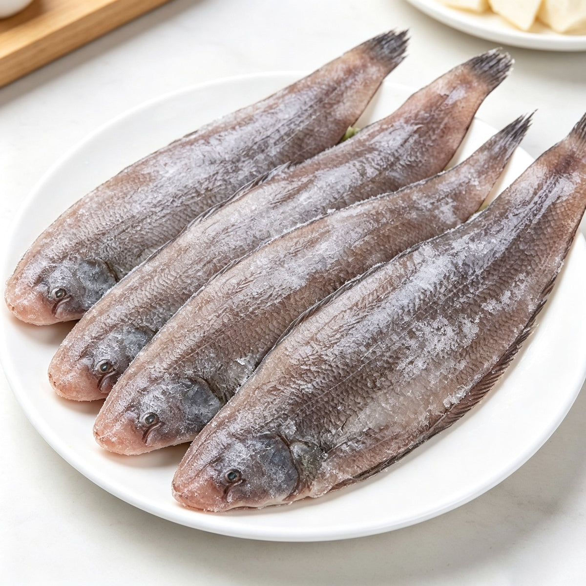 Whole flatfish lined up on a white plate