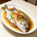 A hand holding a silver sea bream with bright yellow fins